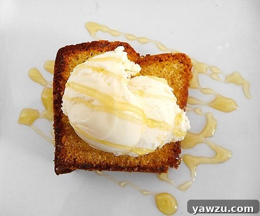 Close-up view of a perfectly sliced Honey-Vanilla Sour Cream Pound Cake, showcasing its moist texture and golden-brown crust. It's topped with a generous scoop of vanilla ice cream and a delicate drizzle of honey on a white plate, ready to be enjoyed.