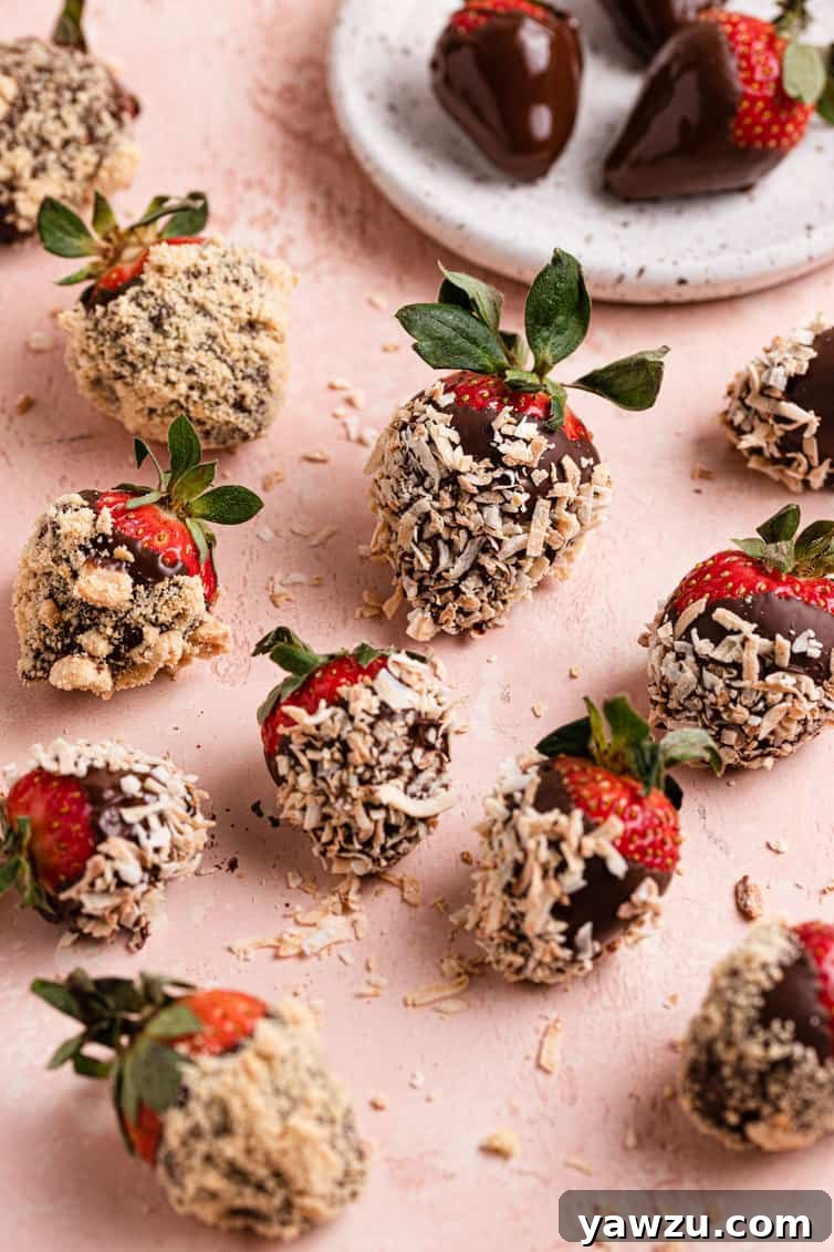 A stunning arrangement of chocolate-covered strawberries, lavishly topped with crunchy nuts and golden graham cracker crumbs, positioned on a vibrant pink counter. In the background, a smaller plate offers a selection of elegantly plain chocolate strawberries, providing a delightful contrast of textures and flavors.
