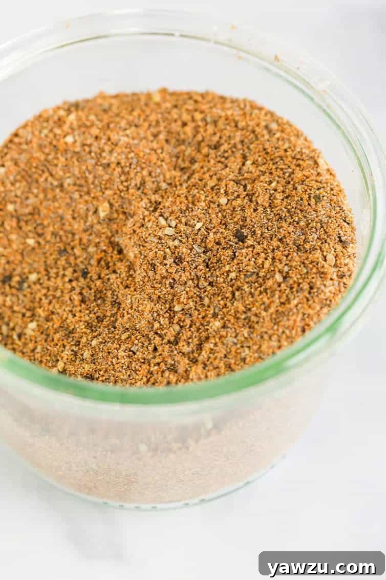 A beautifully arranged glass jar filled with freshly mixed homemade taco seasoning, ready for storage in the pantry.