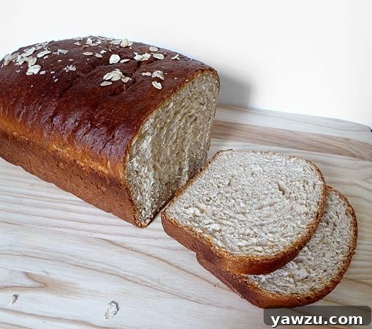 A sliced loaf of homemade honey oatmeal sandwich bread, revealing its soft, dense crumb.