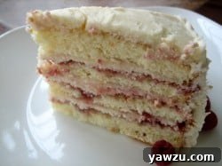 A delectable slice of layered cake showcasing raspberry preserves and cream cheese frosting.