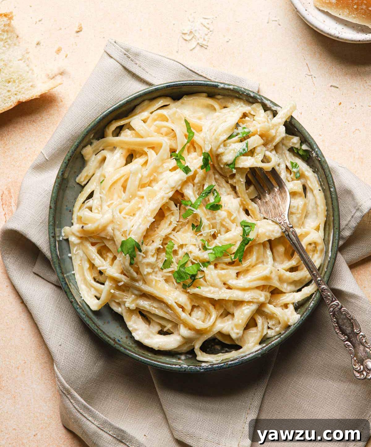 Bowl of fettuccine Alfredo sprinkled with parsley.