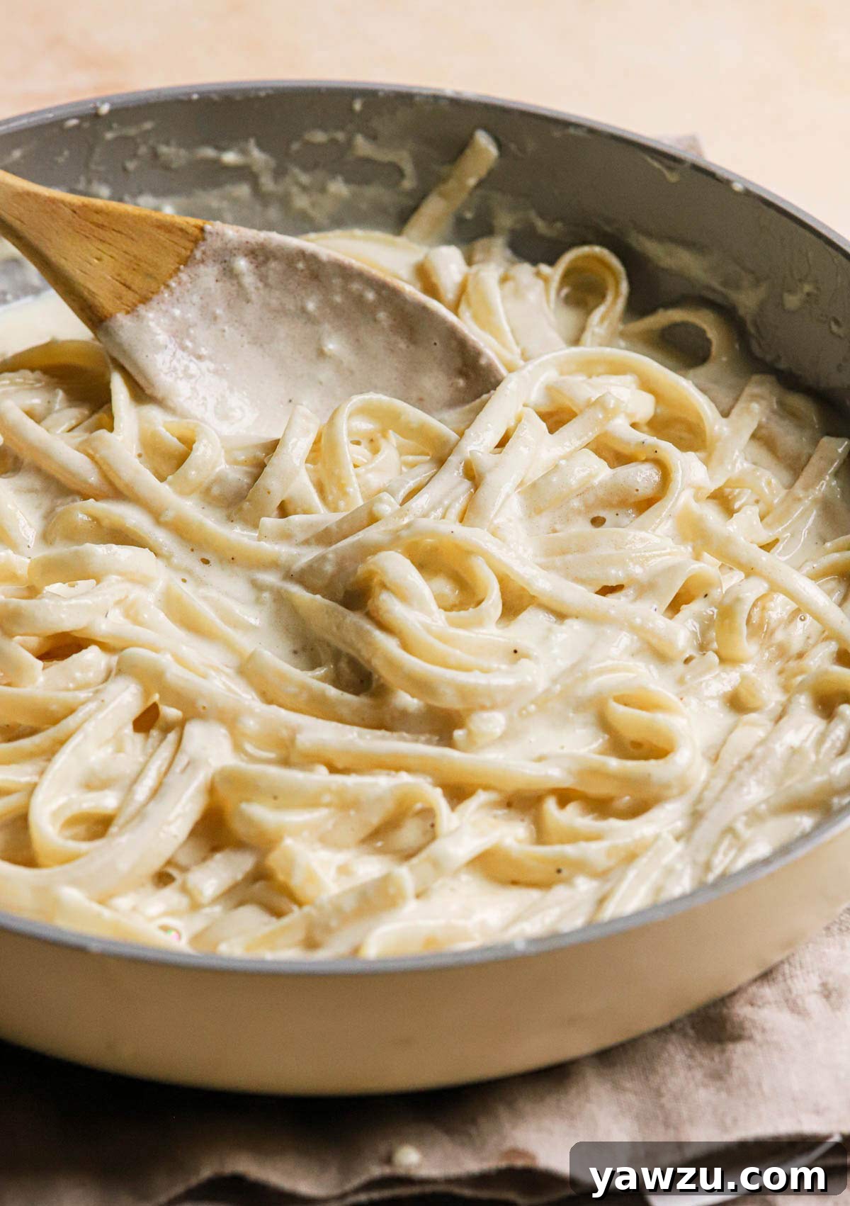 Saucepan full of fettuccine pasta tossed in creamy Alfredo sauce.