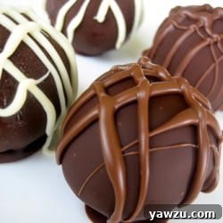 Four cheesecake truffles dunked in dark chocolate with a chocolate drizzle on top.