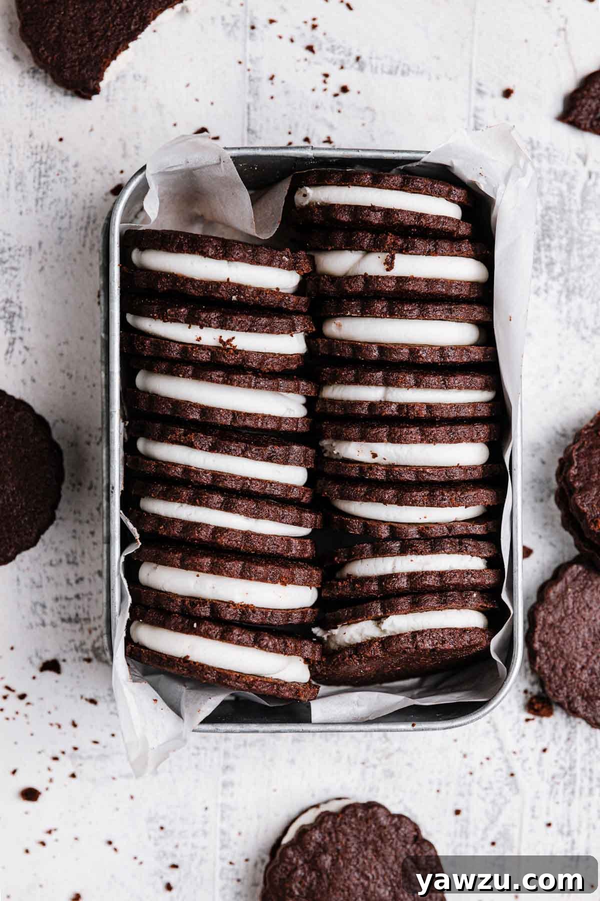 Overhead photo of a tin holding homemade Oreo cookies stacked neatly inside, filling side up.