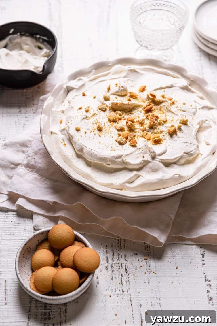A pie pan with homemade banana pudding on a towel with a bowl of eggs in the front left.
