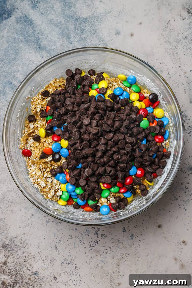 Chocolate chips and M&Ms in bowl of cookie batter.