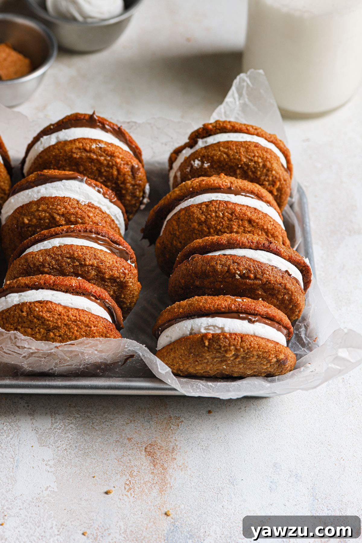 S'mores whoopie pies arranged on a silver tray with a bottle of milk in the background, ready to be served.