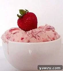 Scoops of strawberry ice cream in a white bowl topped with a fresh strawberry.