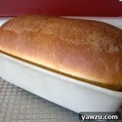 Sandwich bread loaf in a baking pan on a cooling rack.