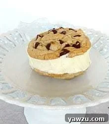 Chocolate chip cookie ice cream sandwich with vanilla ice cream on a white dessert stand.