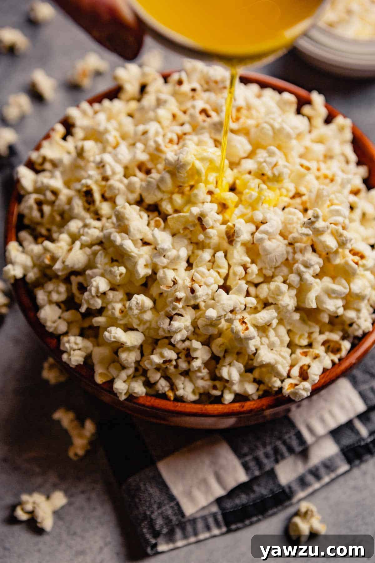 Bowl of popcorn with clarified butter being drizzled over top.