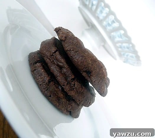 A close-up of three salted chocolate shortbread cookies, stacked neatly on a white plate, highlighting their texture and enticing appearance.