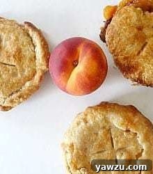 Overhead image of three freshly baked peach pie tartlets, golden brown and glistening.