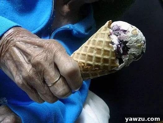 Grandmother happily holding an ice cream cone topped with scoops of toasted almond and candied cherry ice cream.