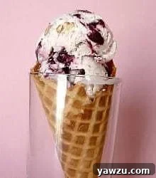 Scoops of toasted almond and candied cherry ice cream in a waffle cone in a glass.