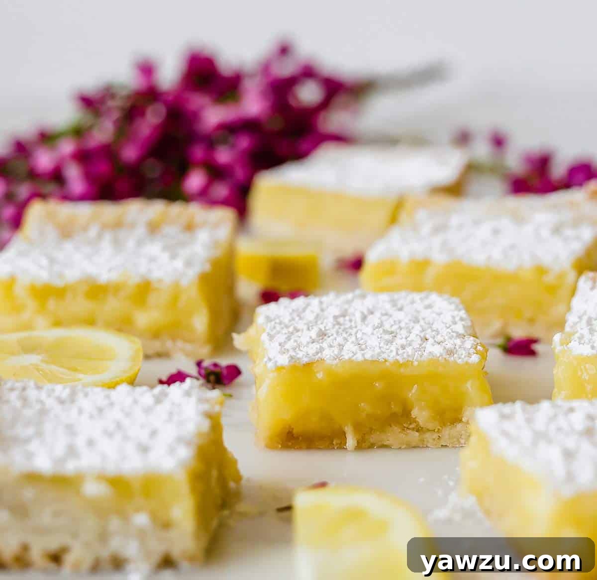 A close-up of perfectly sliced lemon bars resting on a pristine marble surface, showing off their distinct layers and smooth lemon filling.