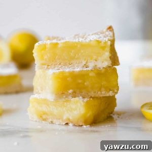 A square image of stacked lemon bars with fresh lemons, representing the final delicious product of the recipe.