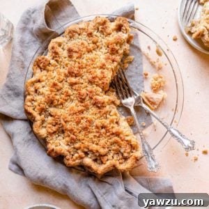 A slice of Dutch apple pie on a white plate, with a fork, ready to be eaten.