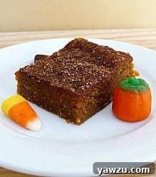 A vibrant close-up of a single Pumpkin Pie Bar, showcasing its soft interior and the glistening cinnamon-sugar crust, ready to be enjoyed.