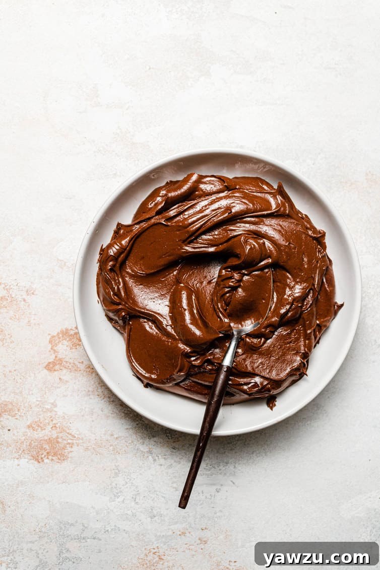 Chocolate frosting in a bowl with a spoon.