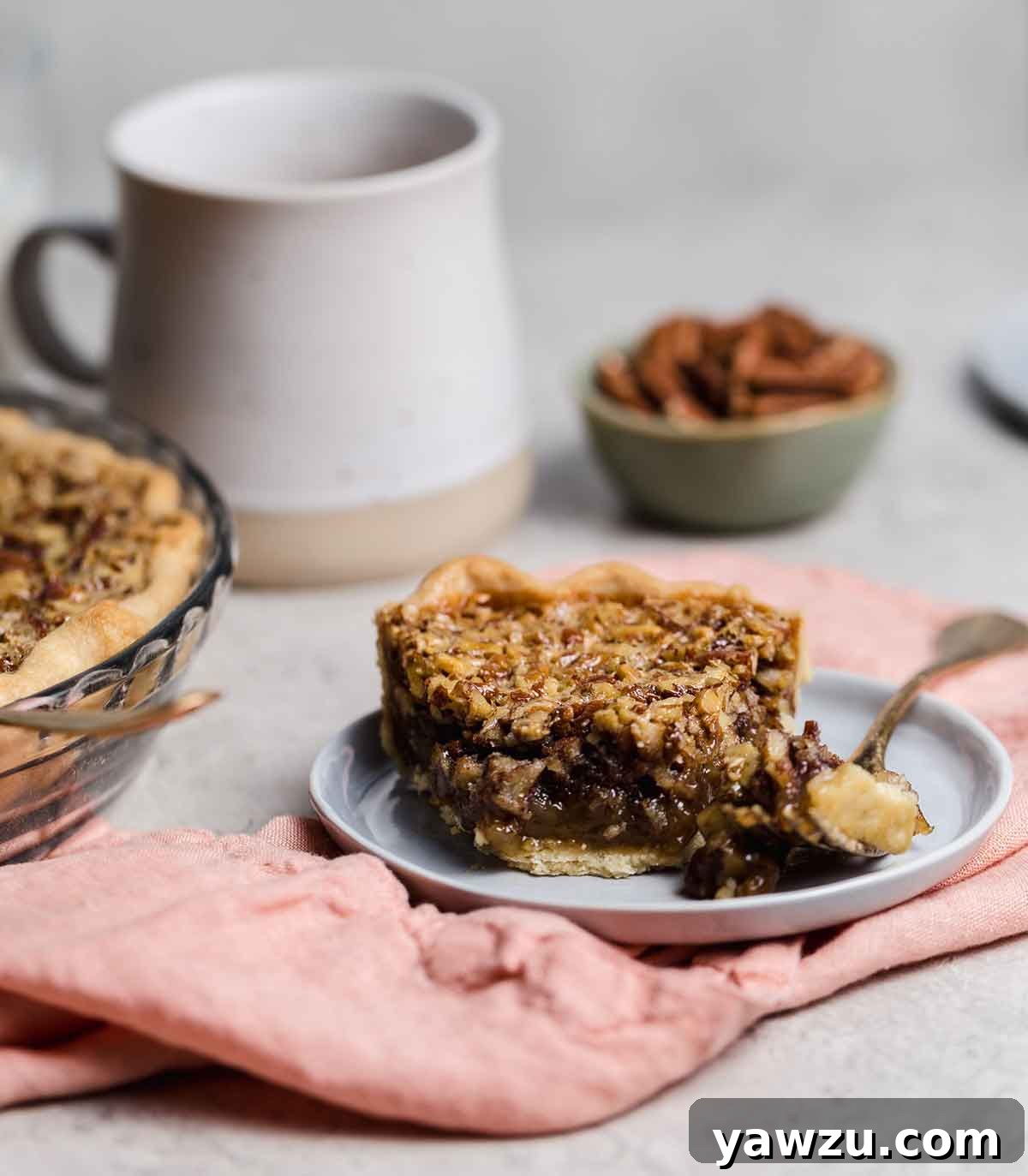 Slice of pecan pie on gray plate with forkful removed.