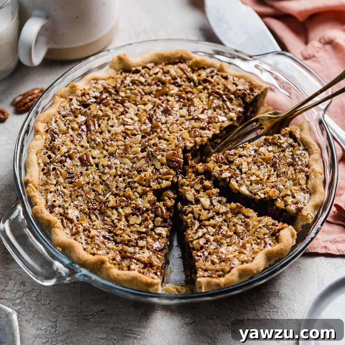 Pecan pie in glass pie dish with two slices cut away and fork in dish.