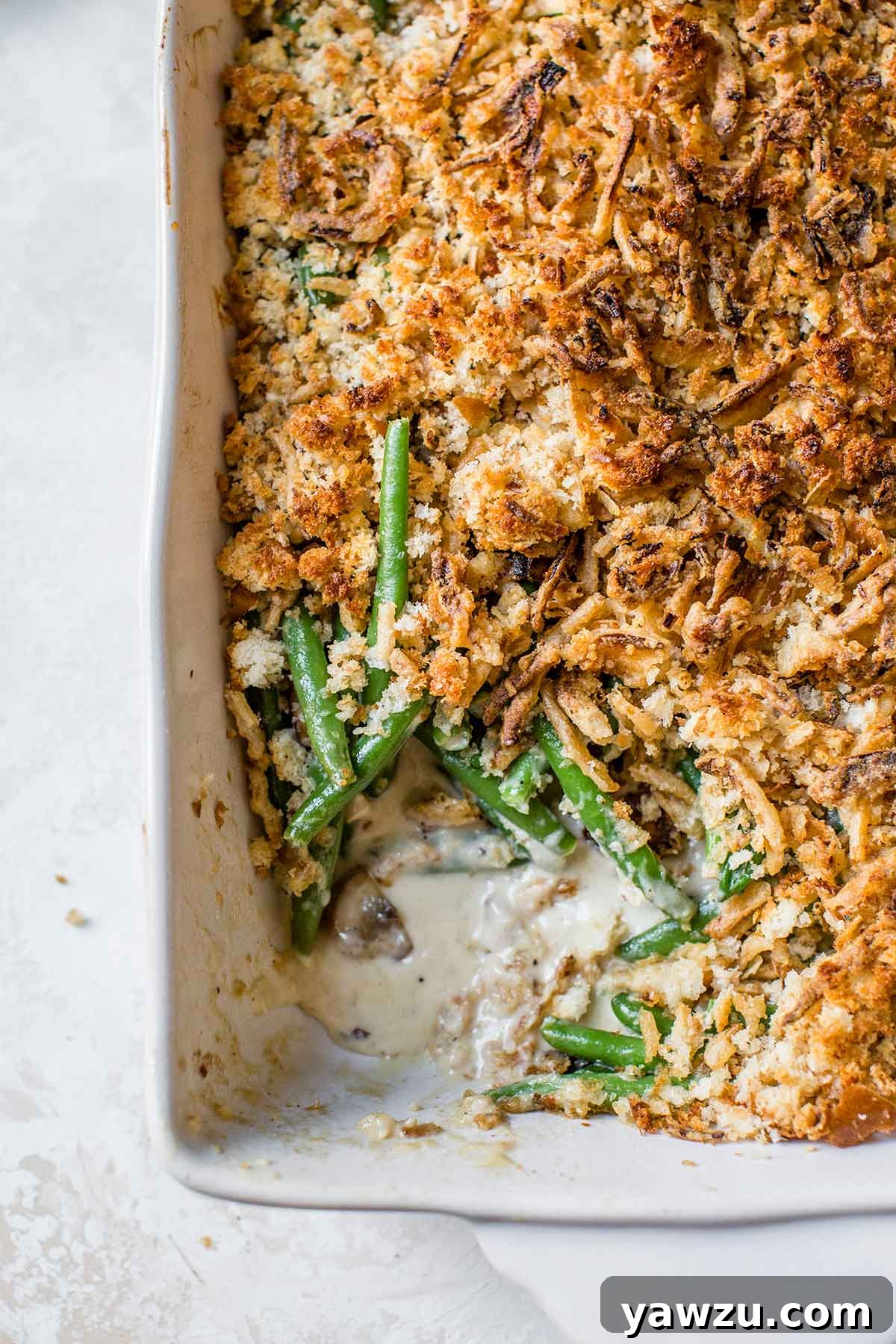 Overhead photo of green bean casserole in a baking dish with a corner scooped out, ready to be served.