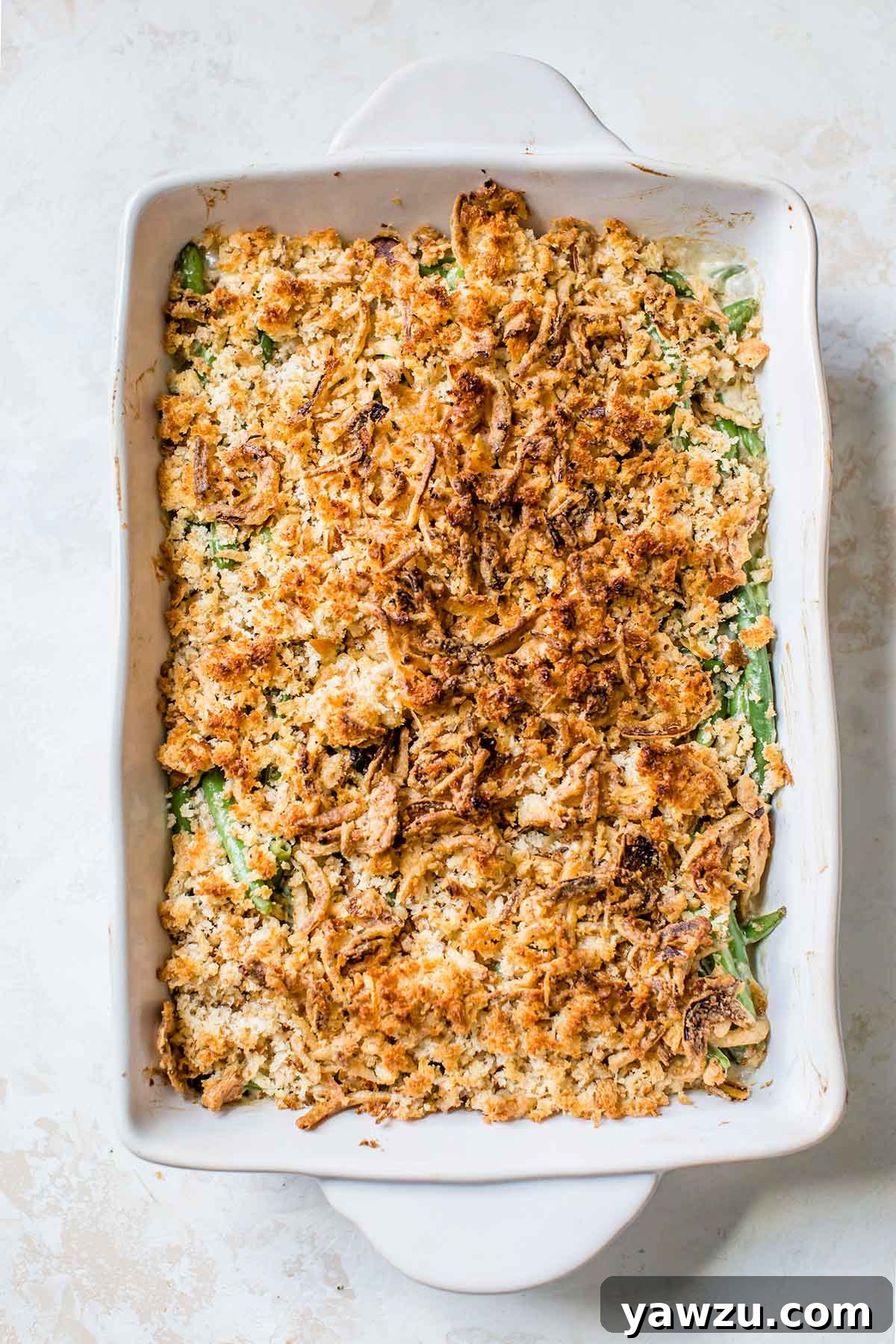 Overhead photo of a freshly baked green bean casserole in a baking dish, golden brown and bubbling, straight out of the oven.