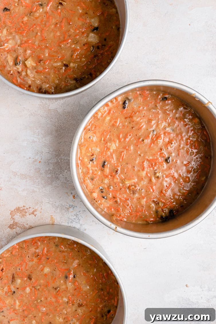 Carrot cake batter in three round cake pans, ready for baking.