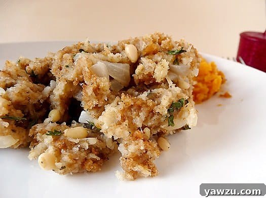 A generous serving of perfectly golden-brown bread stuffing on a white plate, garnished with fresh herbs.