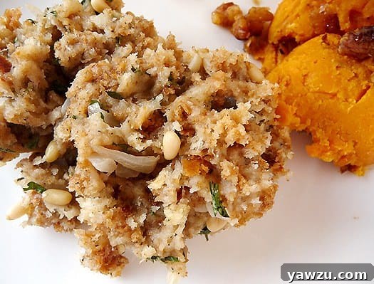 A close-up shot of fluffy bread stuffing with visible herbs and nuts, served on a white plate, ready to be enjoyed.