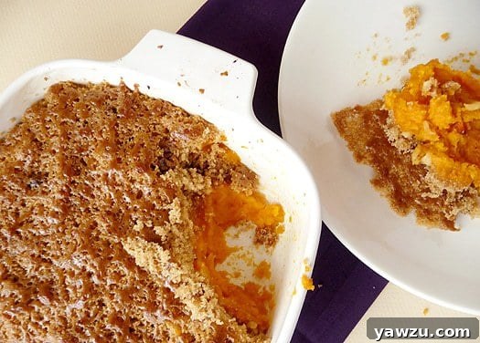 Overhead image of mashed sweet potato brûlée in a casserole dish with a serving scooped out onto a white plate showing the inside texture.
