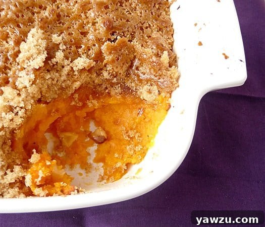 Overhead image of mashed sweet potato brûlée in a casserole dish with a serving scooped out showing the inside texture.