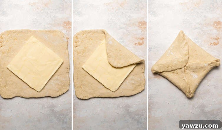 The crucial step of encasing the butter block within the croissant dough, showing the dough being folded over the butter to seal it completely.