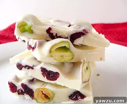 Stack of 4 pieces of pistachio and cranberry white chocolate bark on a white plate, perfectly arranged for serving.