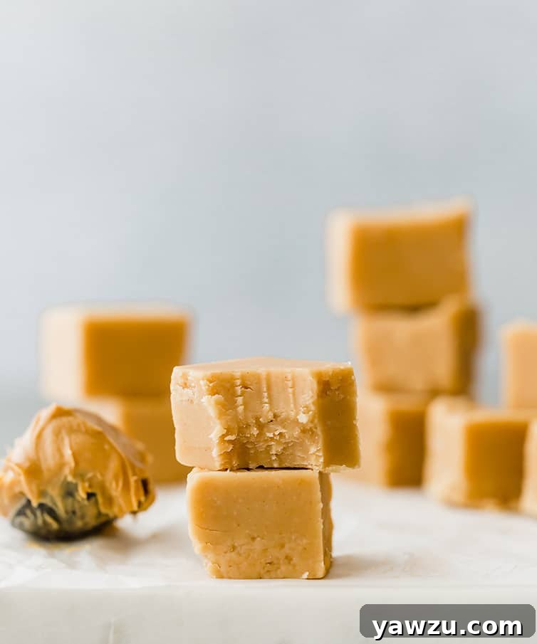Squares of creamy peanut butter fudge stacked neatly on a pristine marble slab, ready to be enjoyed.