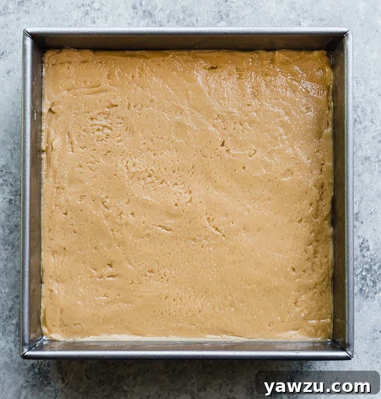 Smooth peanut butter fudge mixture spread evenly into a baking pan, ready for chilling.